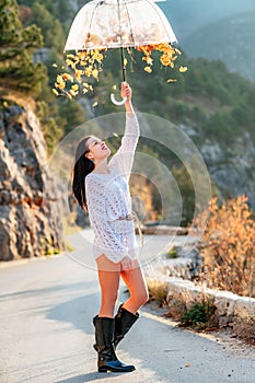 woman umbrella leaves , She holds him over her head, autumn leaves are falling out of him. Beautiful woman in a dress