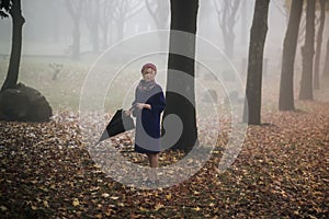A woman with an umbrella in the park in foggy weather.