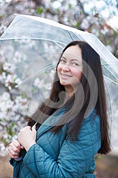 woman with umbrella in a park near almond tree
