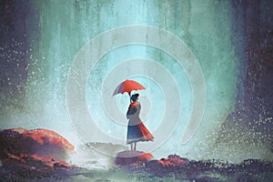Woman with an umbrella standing against waterfall
