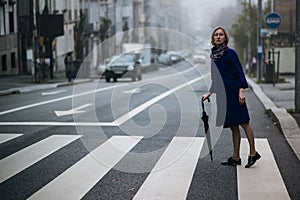 A woman with an umbrella stands outside in the fog.