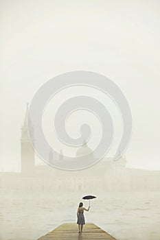 Woman with umbrella walks on a pier to admire the city