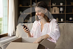 Woman unbox parcel, check order in phone use ecommerce application photo