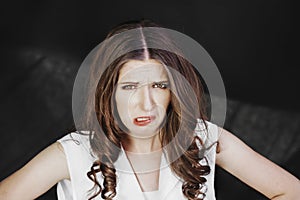 Woman with uncombed hair make a grimace in white shirt stand studio shoot on dark background.