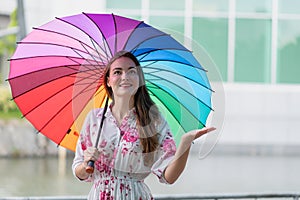 Woman under rainbow umbrella as raining