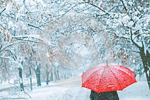 Woman under red umbrella walking in winter snow