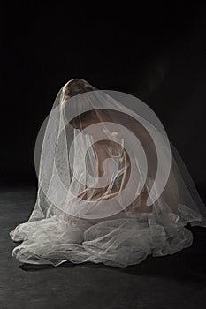 Woman under transparent textile over black