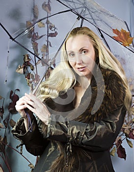 Woman under a transparent umbrella with autumn leaves.