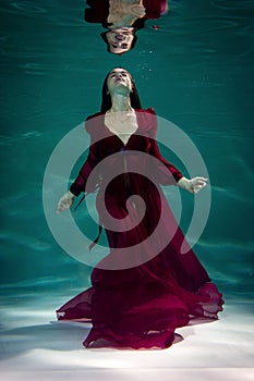 Woman under the water in a red dress.