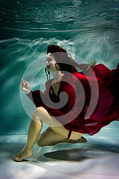 Woman under the water in a red dress.