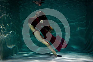 Woman under the water in a red dress.