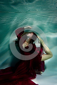 Woman under the water in a red dress.