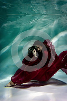 Woman under the water in a red dress.