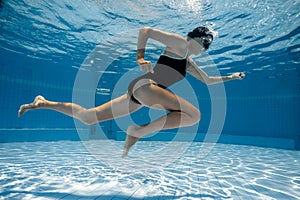 Woman under water runs along a swimming pool