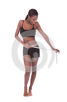 Woman in undergarments measuring waist with tape