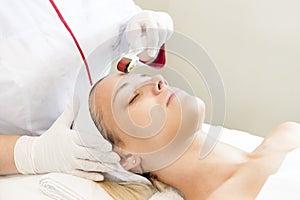 Woman undergoes the procedure of medical micro needle therapy with a modern medical instrument derma roller