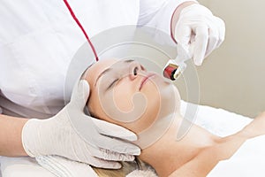 Woman undergoes the procedure of medical micro needle therapy with a modern medical instrument derma roller