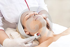 Woman undergoes the procedure of medical micro needle therapy with a modern medical instrument derma roller