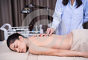 Woman undergoing acupuncture treatment with electrical stimulator on back
