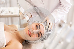 Woman undergoing cosmetic facial treatment using ion bubble attachment