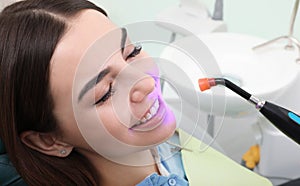 Woman undergoing teeth whitening procedure in clinic photo