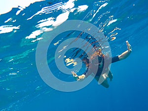 A woman underwater in black swimsuit and mask, loose hair girl snorkeling in mask
