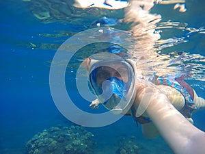 Woman underwater in full face snorkeling mask.