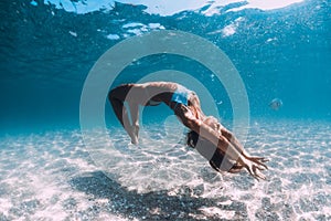 Woman underwater over sandy sea. Freediving in blue ocean