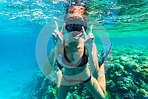 Woman underwater snorkeling with victory happy sign swimming in sea