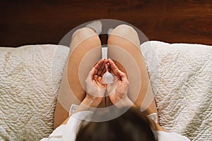 A woman in underwear holds a menstrual cup in her hands