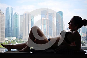 Woman in underwear is on windowsill with view of photo