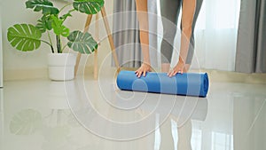 Woman unfolds a yoga mat for practicing in the living room. Girls wear sportswoman legs rolling mat before yoga. healthy lifestyle
