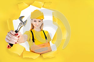 Woman in uniform builder holding metal wrench