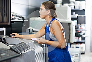 Woman in uniform operating computerised machne to mix paint photo