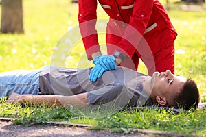 Woman in uniform performing CPR on unconscious man outdoors.