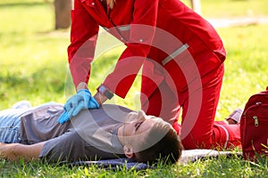 Woman in uniform performing CPR on unconscious man outdoors.