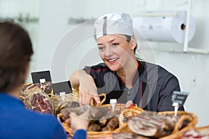 woman in uniform selling delicious smoked salami sausages