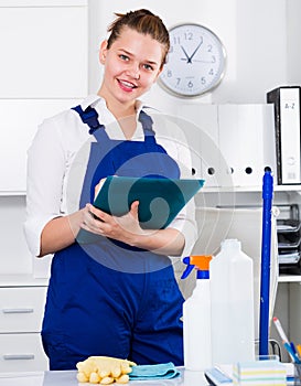 Woman in uniform is signing documents while cleaning