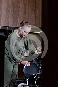 Woman unloading clean dishes from dishwasher at home