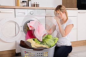 Woman Unloading Smelly Clothes From Washing Machine photo