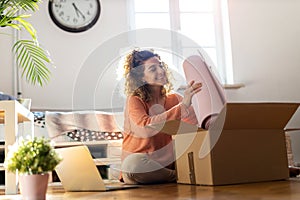 Woman unpacking box with workout equipment at home