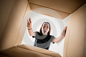 Woman unpacking and opening carton box and looking inside