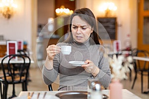 Woman unpleasantly surprised by taste of espresso in coffee house