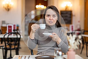Woman unpleasantly surprised by taste of espresso in coffee house