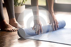 Woman unrolling blue yoga mat, legs close up