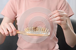 Woman untangling her lost hair from brush, closeup. Alopecia problem