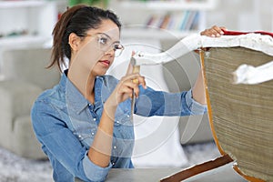 woman upholstering chair in workshop