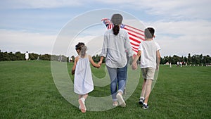 Woman with USA flag walking with kids on meadow