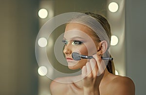 Woman use brush for makeup, visage. Beauty model apply powder on face, cosmetics. Woman with young face skin in beauty