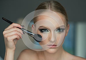 Woman use brush for makeup, visage. Beauty model apply powder on face, cosmetics. Woman with young face skin in beauty